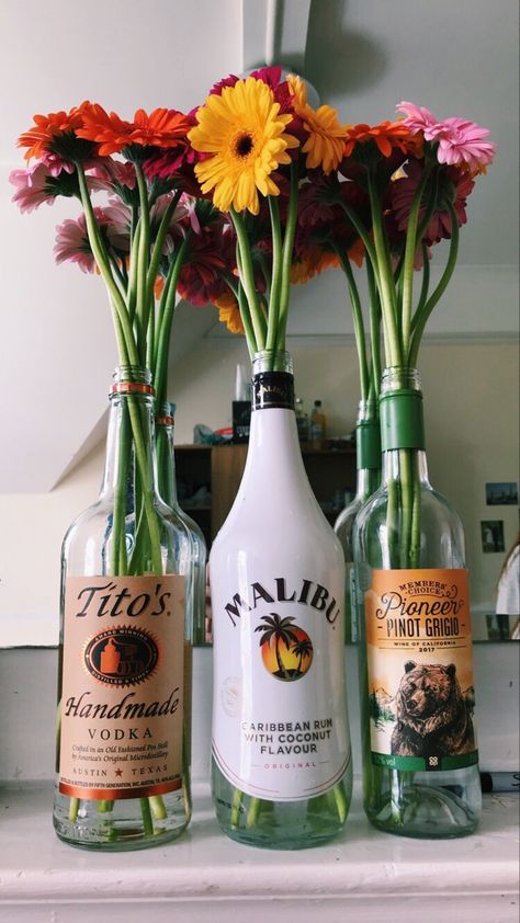 Bright Flowers in Bottles College House Ideas, Flowers In Bottles, Alcohol Bottle Decorations, College House Decor, Girl Apartment Decor, Be Aesthetic, College Room Decor, College House, College Apartment Decor