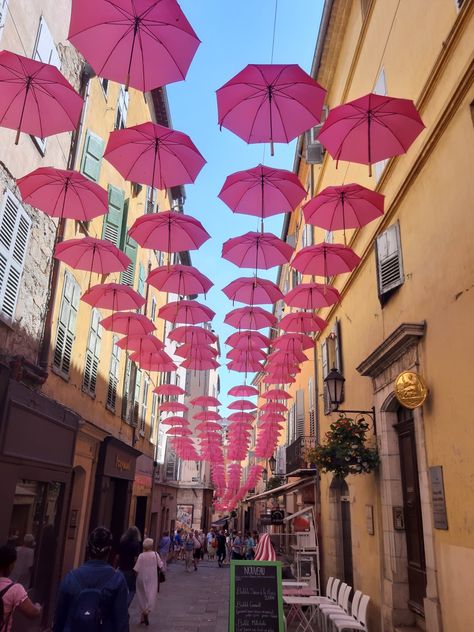 Photo d'une ruelle de Grasse avec des parapluies roses suspendus au-dessus de celle-ci. Grasse France, Pink Street, French Riviera, South Of France, Beautiful Places, Umbrella, Fair Grounds, Street View, Neon Signs