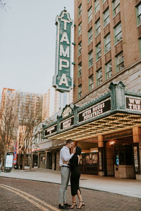 Bride in all black standing with groom in front of tampa theater sign Downtown Rooftop Engagement Photos, Downtown Tampa Elopement, Hyde Park Tampa Photoshoot, Tampa Theatre Photoshoot, In Town Photoshoot, Down Town Photoshoot Couples, Couples Photo Shoot Downtown, Editorial Downtown Engagement Photos, Downtown Tampa Photoshoot