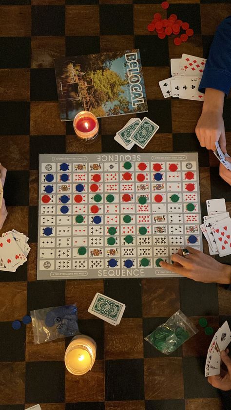 top-down overhead photo of sequence (the board game) splayed across a black and brown wooden coffee table as three people are playing the game, two candles are lit on the table Checkers Game Aesthetic, Family Board Games Aesthetic, Cabin Weekend Activities, 30th Birthday Cabin Weekend, Cozy Cabin Vibes, Board Game Coffee Table, Cabin Party Aesthetic, Family Game Night Aesthetic, Summer Cabin Aesthetic