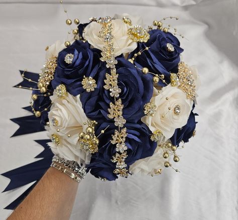 Handmade quinceañera - sweet 16th bouquet with Navy and Champagne roses. Finished off with Gold brooches. Décor can be changed upon request. *This is a made to order bouquet* *Please note brooches can change in style based on availability* Quincenera Dresses Blue And Gold, Quinceanera Navy Blue Decorations, Navy Blue Masquerade Quince, Navy Blue Quince Cake Ideas, Navy Blue Quince Bouquet, Quince Dark Blue Theme, Quince Blue And Gold, Quince Decorations Blue And Gold, Midnight Blue And Rose Gold Wedding