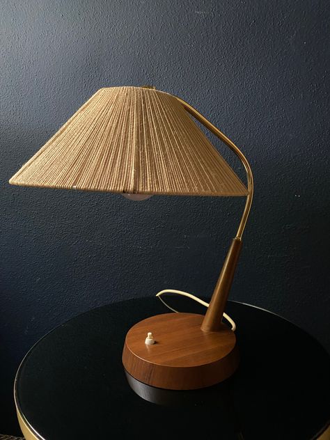 This desk lamp is the quintessential Mid-Century Modern design: a conical sisal shade, an elegantly shaped brass arm and round wooden base with a white push button switch. Made by the German-Swiss manufacturer Temde and hailing from the late 50s to early 60s this lamp is still in great condition - a testimony to the craftsmanship and quality martials used when making this lamp. The lamp is designed for an E27 bulb and emits a warm and comforting light through its sisal shade.  This is a compact Mid Century Lamp Shades, Rattan Lampshade Bedroom, Lamps Mid Century Modern, 70s Lamp, Mid Century Modern Lamp, Applied Art, Basement Bedroom, Mid Century Lamp, Early 60s