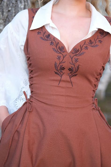 Along the bust and waistline are two fully adjustable side panels. The lacing can be taken in or out in order to give you a bit more room to cinch, move and change. The dress is adorned by delicate embroidery along the sweetheart neckline, inspired by the traditional national costumes of Norway. The dress features a midi length skirt and a high back for coverage and support. Cottagecore, embroidery dress, renfaire, fantasy clothes, historical clothes, viking dress, linen dress. Embroidery Patterns Clothing, English Traditional Clothing, Vintage Dress Ideas, Vintage Southern Outfits, Quick Change Dress Diy, Embroidery On Linen Dress, Side Lace Up Dress, Cute Sewing Ideas Clothes, Anne With An E Inspired Outfits