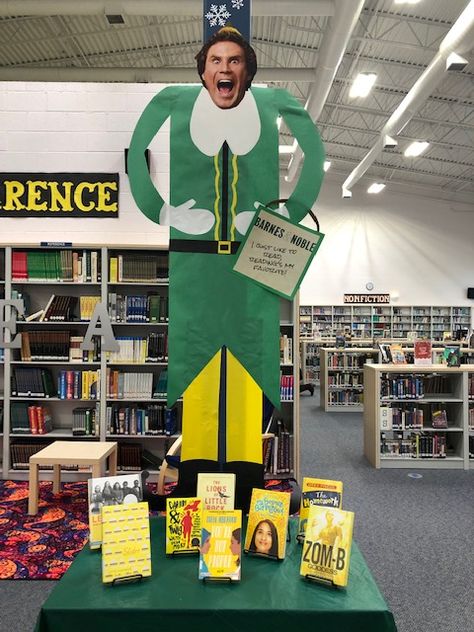 Buddy the Elf in the my school library. Made from bulletin board paper. The bag says "I just love to read, reading's my favorite." Buddy The Elf Library Display, Buddy The Elf School Hallway, Elf Library, Grinch Library Bulletin Boards, Library Christmas Bulletin Boards, Christmas Library Bulletin Boards, Middle School Library Displays, Holiday Library Displays, School Library Bulletin Boards