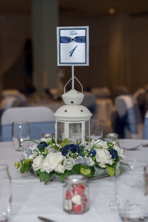 Ikea lantern wedding centrepiece, with artificial flowers, fairy lights & table number. Wedding Lantern Decor Fairy Lights, Wedding Lantern Fairy Lights, Fairy Lights Table, Lantern Centerpieces With Table Numbers, Ikea Lantern Centerpiece Wedding, Blue Paper Lanterns Wedding, Decor With Lanterns, Ikea Lantern, Ikea Lanterns