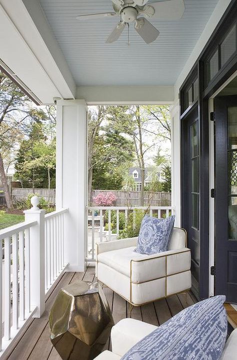 Gorgeous covered porch,with a ceiling fan over ivory upholstered chairs with brass trim adorned with blue medallion pillows alongside a brass geometric stool table. Blue Beadboard, Haint Blue Porch Ceiling, Blue Porch Ceiling, Blue Porch, Spring Interior Design, Blue Ceiling, Haint Blue, Porch Ceiling, Blue Ceilings