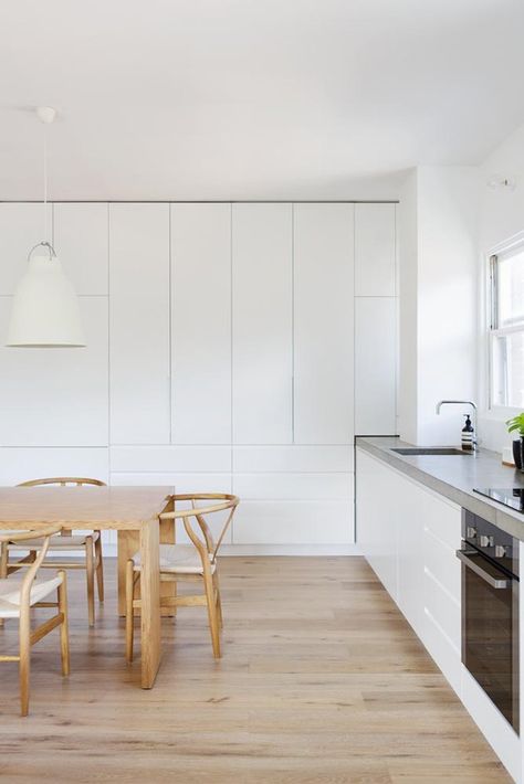 White floor-to-ceiling cabinets in minimalist kitchen with wood dining table and chairs Floor To Ceiling Cabinets, Minimalist Kitchen Design, Floor To Ceiling, Kitchen Crafts, White Floors, Built In Cabinets, Trendy Kitchen, Minimalist Kitchen, Kitchen Cupboards