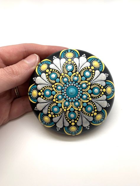 This is an original hand painted dot mandala on a smooth stone. I make all of these stones using silicone molds and plaster. I then paint them using acrylic paints, and coat them for a long lasting glossy finish. These stones make wonderful gifts and are a lovely addition to your indoor decor. My stones are water resistant with the sealer, but please note that they are not water proof and should not be left out in the weather elements.  These stones are hand painted and therefore small imperfections are normal. MEASUREMENTS:  Height: 1.0" Width: 3.0"  RETURN POLICY: Unfortunately I can not duplicate an item if it is damaged. If you are unhappy with your item, I will refund the full amount upon the return of your item. I will except exchanges as well. PERSONALIZATION: I can paint names, quo Mandala Art On Stone, Dot Art On Rocks, Mandela Rock Painting Patterns, Painted Rock Designs, Dot Painting Flowers, Mandala On Stone, Dot Painting Patterns, Mandela Rocks, Mandela Rock Painting