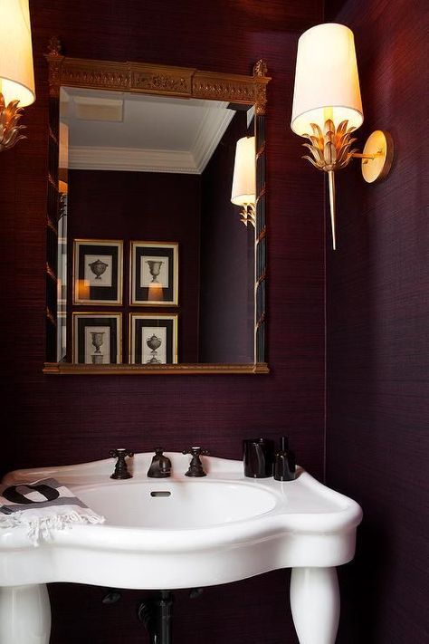 Purple powder room boasts walls clad in purple grasscloth lined with a black and gold French mirror over a Parisian pedestal sink fitted with bronze fixtures lit by gold wall sconces, Worlds Away Delilah Gold Leaf Sconce. Purple Powder Room, Burgundy Bathroom, Bronze Fixtures, Sconces Living Room, Purple Bathrooms, French Mirror, Transitional Bathroom, Master Bath Remodel, Indoor Wall Sconces