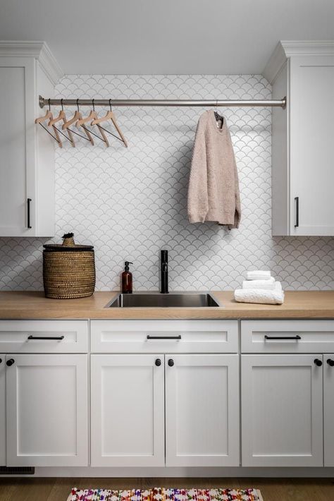 Stylish laundry room design with white cabinetry, wood countertop, modern backsplash tile, and hanging rod for drying clothes. A perfect combination of functionality and contemporary style.Laundry room with white cabinets, wood countertop, backsplash tile, and drying rod.#LaundryRoomDesign #HomeOrganization #InteriorDesign #HomeRenovation #ClarkAndAldinePin Laundry Room Ideas White Cabinets, Tile In Laundry Room, Laundry Room Tile Backsplash, Laundry Room With White Cabinets, Modern Backsplash Tile, White Cabinets Black Hardware, Laundry Room And Bathroom, Bright Laundry Room, White Cupboard