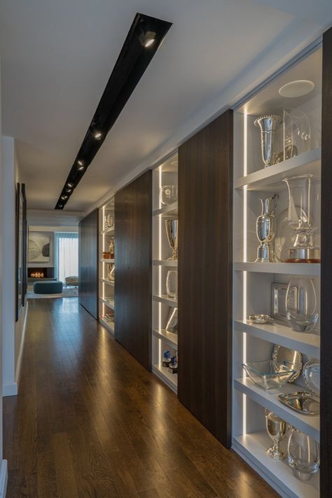 Illuminated modern shelving lines a hallway. Recessed vertical lighting and a recessed track light system in the ceiling create a contemporary display area. Modern interior design by Walker Architects. Awards Display Wall, Award Shelves, Trophy Display Shelves, Gallery Lights, Trophy Cabinets, Hallway Landing, Display Shelf Design, Display Cabinet Design, Trophy Display