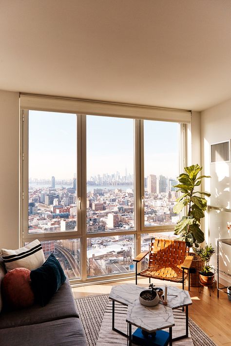 small space apartment with floor-to-ceiling windows and Eric Trine chair, West Elm coffee tables, Queens, New York City Floor To Ceiling Apartment Windows, Ceiling To Floor Windows Apartment, Apartment With Floor To Ceiling Windows, Floor To Ceiling Windows Living Room Apartment, City Home Aesthetic, Bedroom With Floor To Ceiling Windows, Small Apartment New York, Floor To Ceiling Window Apartment, New York Small Apartment