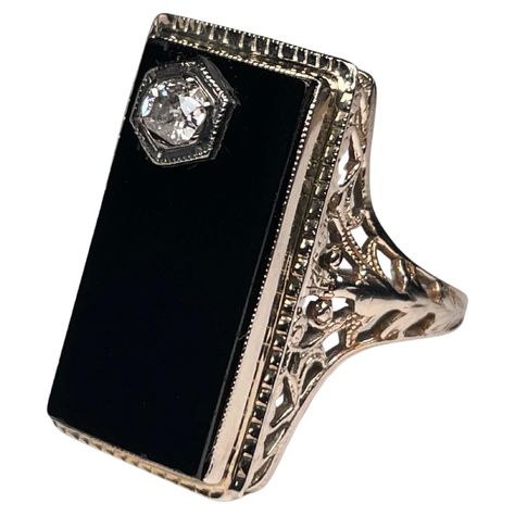 This is an Art Deco 14K white gold, diamond and onyx cocktail ring. It depicts a rectangular black onyx top in white gold bezel setting. The onyx has a reeded gold frame. A round cut diamond on prong setting embellishes one of the corner of the onyx. Each shank of the ring is adorned with a reticulated work made of leaves and hearts. The onyx stone symbolizes courage, power and good fortune. Vintage Onyx Ring, No Ordinary Girl, Gold Pinky Ring, The Bling Ring, Vintage Art Deco Rings, Carnelian Ring, Black Onyx Ring, Celtic Jewelry, Deco Jewelry