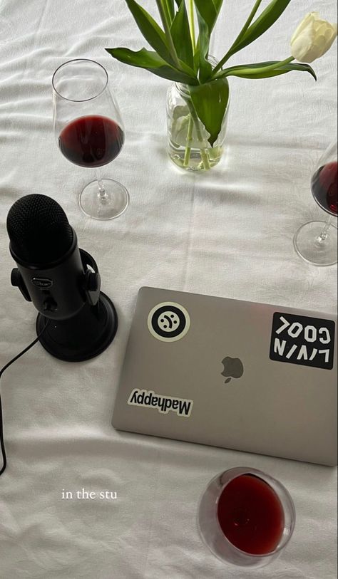 A white table with a laptop, wine glasses filled with red wine, a vase of tulips, and a black microphone. Podcast Aethestic, Podcast Recording Aesthetic, Recording A Podcast, Starting A Podcast Aesthetic, Podcast Aesthetic Wallpaper, Podcast Cover Ideas Aesthetic, Podcast Girl Aesthetic, Social Media Content Creator Aesthetic, Podcast Microphone Aesthetic