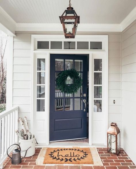 Navy blue front door. Southern front porch inspiration with navy blue front door and a hanging copper lantern by Primo. Sherwin Williams Misty SW 6232 blue porch ceiling, Pearly White trim SW 7009, Charcoal Blue front door SW 2739, and Benjamin Moore Revere Pewter siding HC-172. Wayfair faux cedar wreath and Hello doormat. #winterporchdecor #frontdoor #navyfrontdoor #frontporch #reverepewter #exteriorcolorpalette #blueporchceiling #copperlantern #charcoalblue Navy Blue Front Door, Navy Front Door, Front Porch Inspiration, Yellow Front Doors, Blue Front Door, Front Door Paint Colors, Door Paint Colors, Painted Front Doors, Lavender Flower