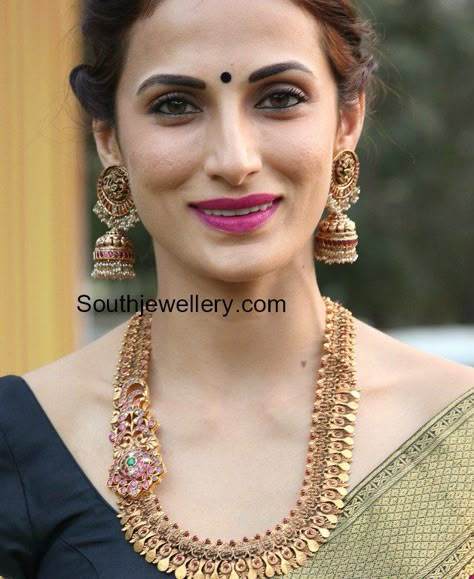 Shilpa Reddy in an antique gold haram with ruby side pendant paired with matching antique jhumkas. Shilpa Reddy Jewellery, Kasu Mala With Pendant, Antique Jhumkas Gold Temple Jewellery, Antique Gold Haram, Antique Jhumkas, Pearl Haram, Papidi Billa, Shilpa Reddy, Kasu Mala