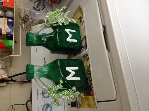 Noise Makers for Football Games. Juice bottles spray painted green.  Rocks inside to make the noise. Ribbons added for color. Noise Makers For Football Games, Pep Rally Noise Makers, Diy Noise Makers, Football Noise Makers, Football Banquet Centerpieces, Green Rocks, Banquet Centerpieces, Robotics Club, Football Banquet