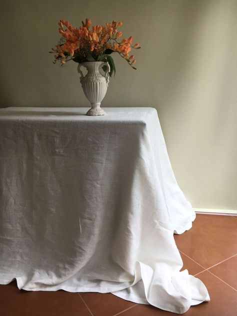 "A true classic. White linen tablecloth in a stunning medium weight with the beautifully distinct linen texture.  Made from 100% pure linen it will be a fantastic addition to your table. Drapes beautifully. Classic quality. Dress your table up for special events or enjoy the simple touch.  Layer with another tablecloth in natural taupe for a stylish look.  Available in various sizes. We can also make a round tablecloth with maximum 54\" in diameter.  Please allow for ONE week to hand-tailor the White Linen Tablecloth Wedding, White Linen Table Cloth, Small Apartment Table, White Linen Table, White Linen Tablecloth, Dark Wood Table, Linen Table Cloth, Simple Table Settings, Breakfast Nooks