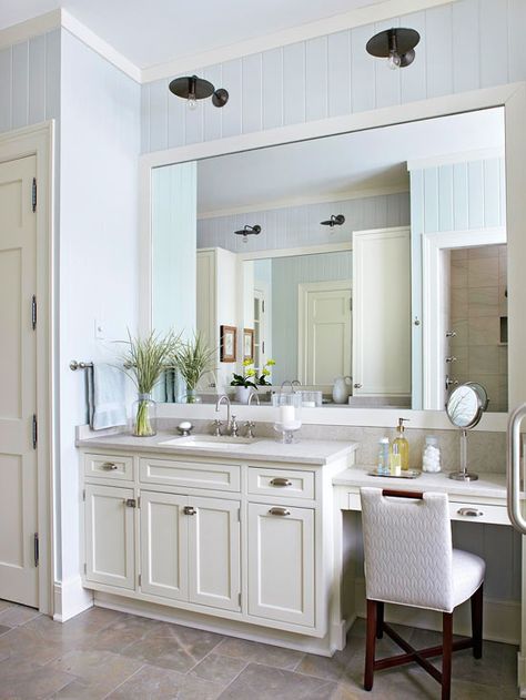 Antique sconces hang above the oversize mirror and add unexpected flair to the light and bright bathroom. The dark finish on the light fixtures adds weight to the room and helps unify the dark legs of the chair and the cabinet hardware. Their position above the vanity also provides task lighting for makeup application and grooming. Vanity With Makeup Area, Best Bathroom Lighting, Bathroom With Makeup Vanity, Large Bathroom, Bright Bathroom, Bad Inspiration, Vanity Ideas, Bathroom Decorating, Bath Ideas