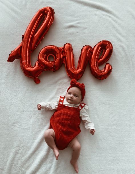 Small Baby girl laying on a white blanket wearing a red and white romper and a red baby bow with a balloon foil spelling the word love for Valentine’s Day photoshoot Valentines Day Newborn Pictures, Valentines Baby Photoshoot Ideas, 4 Month Valentine Pictures, Valentines Day Newborn Photoshoot, Newborn Baby Valentines Photoshoot, Valentines Pictures Baby, Valentines Baby Pictures, 1 Month Old Baby Pictures Valentines, Infant Valentine Pictures