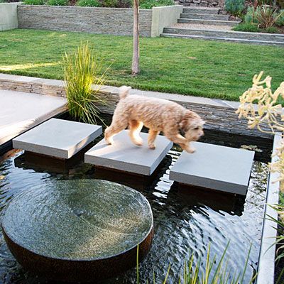 Water crossing  Bluestone pavers traverse this water feature in Alamo. The designer attached them to concrete pillars built into the bottom; each one is cantilevered 4 inches out from its pillar. The dark Mexican pebbles lining the pool and the dark-hued pillars make the water more reflective. The fountain in the foreground is made from an old millstone, polished smooth on top. Pond Backyard, Bluestone Pavers, Modern Water Feature, Taman Air, Backyard Pond, Outdoor Water Feature, Pond Ideas, Garden Walkway, Water Features In The Garden