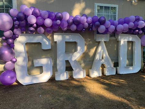 purple ballon arch with big cardboard letters spelling grad for graduation Purple Graduation Party Ideas Decoration, Graduation Party Decor Purple, Purple Graduation Decorations, Purple Black And White Graduation Party, Purple And White Graduation Party, Light Purple Graduation Party, Purple And Gold Graduation Party, Pink And Purple Graduation Party, Purple And Silver Graduation Party Ideas