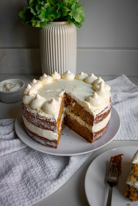 A carrot cake with two tiers and cream cheese frosting with a slice cut out of it. The slice is sitting on a plate next to the cake. Tiered Carrot Cake, Names On Cakes Ideas, Cute Carrot Cake Decorations, Carrot Cake Wedding Cakes Simple, Cake Decorating Carrot Cake, East Birthday Cakes, Carrot Cake Presentation, Easy Carrot Cake Decorating Ideas, Birthday Cake Carrot Cake