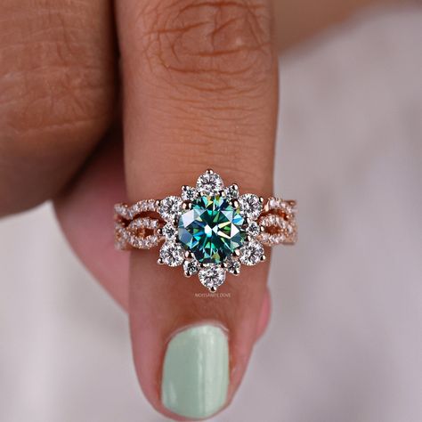 Teal Moissanite Engagement Ring Set, 2.27 TCW Round Brilliant Cut Moissanite Bridal Set, Vintage Halo Ring, Twisted Curved Matching Band, Blue Green Moissanite Ring, Color Moissanite Ring, Ring for Women, Ring for Her, Anniversary Gifts, Wedding Ring Set, Rose Gold Rings, Crossover Ring, Stackable Band, Moissanitedove 𝐈𝐭𝐞𝐦 𝐒𝐩𝐞𝐜𝐢𝐟𝐢𝐜𝐚𝐭𝐢𝐨𝐧: Ring's Center Stone Shape: Round Brilliant Cut ◼Carat Weight: 1.34 CT ◼Dimension: 7.00*7.00*4.55 MM ◼Color: Teal or Blue Green ◼Clarity: VVS ◼Cut Grade: Excellent Ring and Band's Side Stone Shape: Round Cut  ◼Carat Weight: 0.93 TCW ◼Dimension: 1.10 & 1.70 & 2.70 MM ◼Color: Colorless ◼Clarity: VVS ◼Cut Grade: Excellent 𝐌𝐞𝐭𝐚𝐥 𝐝𝐞𝐭𝐚𝐢𝐥𝐬: 1. We can make this item in 10KT, 14KT, and 18KT gold. 2. You can choose any metal like white go Colored Moissanite Ring, Colored Moissanite, Sapphire Engagement Ring With Halo, Teal Moissanite Engagement Ring, Country Style Wedding Rings, Unique Wedding Rings Engagement Bridal Sets, Flat Wedding Rings Women, Rare Gemstone Engagement Ring, Unique Engagement Rings Moissanite