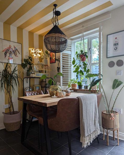 Dining room with yellow and white striped walls, brown leather bench seats, wooden table, and lots of plants Painted Dining Room, Boston Apartment, Painted Stripes, Apartment Dining Room, Bench Seats, Striped Walls, Rental Apartment, Parisian Cafe, Dining Room Makeover