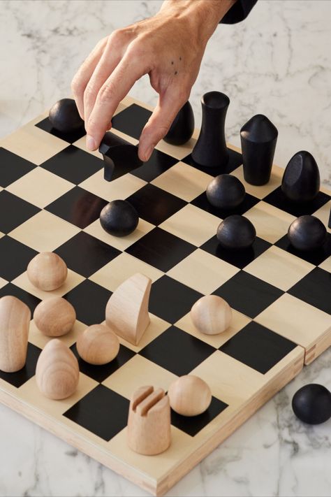 Foldable wooden chess set designed by Panisa Khunprasert. This chess set features minimalist turned-wood chess pieces that evoke modern sculptures. Subtle details are employed to identify the various pieces: a diagonal slice on the oval-shaped Bishop suggests a liturgical headpiece; two deep grooves create castle turrets for the cylindrical Rook; the Knight’s arched lines follow the shape of a horse’s head. Flat Chess Pieces, Clay Chess, Modern Chess Set, Chess Design, Knight Chess, Moma Design, Wood Chess, Chess Sets, The Knight