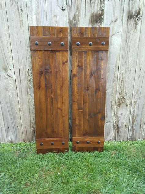 "2 \"Board N Batten\" style Rustic Cedar Shutters, with Black Clavos nails for exterior use. Color in this listing: Early American. Each shutter is made with 5/8\" thick boards. The \"Board N Batten\" style is made with 3 vertical boards joined together with 2 horizontal boards as shown. There are 6 Clavos Nails on each shutter - 3 on the top batten and 3 on the bottom batten. CONSTRUCTION - Our shutters are made with rough cut western cedar wood. They are strongly built as shown being nailed, g Exterior Cedar Shutters, Wood Shutters Exterior, Nails Board, Shutter Hardware, Rustic Shutters, Cedar Shutters, Cedar Boards, Rustic Hardware, Home Exterior Makeover