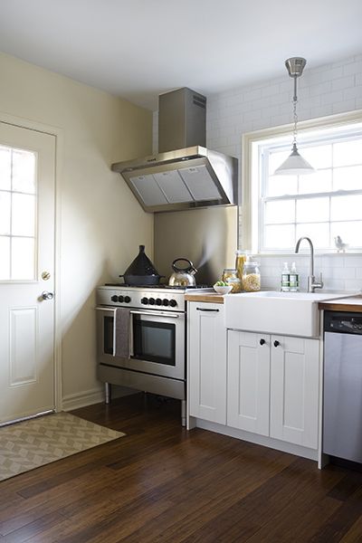 Beautiful kitchen with wide framed shaker front cabinets paired with oil-rubbed bronze hardware and butcher block countertops below a ceiling height subway tiled backsplash. The kitchen includes a footed stainless steel stove up against the wall which pairs with a stainless backsplash and stainless vent hood. An apron kitchen sink, Ikea Domsjo Sink Bowl, with gooseneck faucet stands beside the stainless steel dishwasher below the large kitchen window illuminated by a polished nickel pendant ... Stove Against Wall, Kitchen Sink Wall No Window, Kitchen Sink Ideas, Back Splashes, Block Countertops, Best Kitchen Sinks, Kitchen Furniture Storage, Old Kitchen Cabinets, Sink Ideas