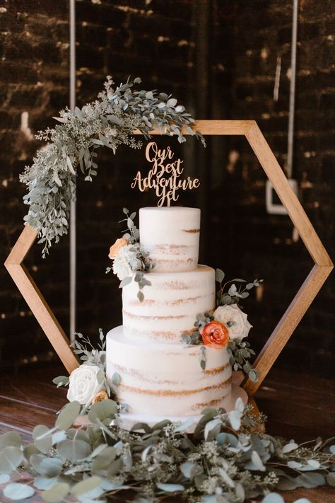 If you're looking for a modern twist on a classic wedding treat, this show-stopping three-tier naked white wedding cake on a geometric cake stand is sure to be the highlight of your special day. Not only will this gorgeous cake be a showstopper, it will also add a touch of sophistication to the celebration with its intricate diamond design. With layers of tender buttercream and moist white sponge, this cake is sure to be a hit with your guests at the reception. Erin Morrison Photography Wedding Cakes Stands Ideas, Hexagon Wedding Cake Topper, Modern Boho Wedding Backdrop, Wedding Cake Arch Stand, Cake Stand Backdrop, Octagon Centerpiece Wedding, Honeycomb Wedding Decor, Wedding Hexagon Centerpieces, Hexagon Table Centerpieces