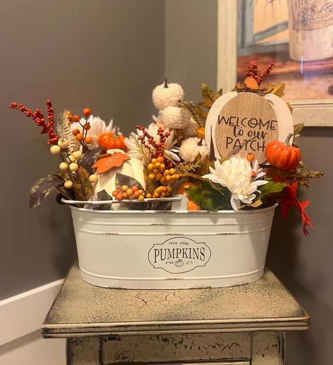 Embrace the warmth and charm of autumn with our Fall-Themed Farmhouse Bucket Arrangement. This delightful arrangement brings together the essence of the season in a rustic and elegant display. Each basket is crafted with care, combining a variety of autumnal elements that evoke cozy, nostalgic feelings. Features: Farmhouse Bucket: A sturdy, metal bucket with a timeless farmhouse design, perfect for displaying on a porch, table, or mantle. Textured Accents: Featuring faux pumpkins, gourds, and orange berries, adding a touch of harvest charm to the arrangement. Rustic Touches: Finished with a pumpkin block sign for the ultimate cozy fall vibe. 15.2x7.3x5.25" Fall Basket Decor, Fall Baskets, Tin Tub, Bushel Baskets, Fall Front Porch Decor, Faux Pumpkins, Fall Items, Farmhouse Fall Decor, Fall Deco