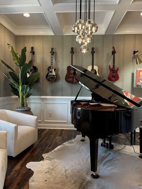 Music Room interior design. Piano on cowhide rug. Two side chairs. Vertical wallpaper design. Guitars hanging on wall. Coffered ceiling. Hanging globes chandelier. Music Room With Piano And Guitars, Piano Room Wallpaper, Grand Piano Music Room, Nashville Interior Design, Rustic Music Room, Music Room With Piano, Piano Sitting Room, Music Room In House, Classical Music Room