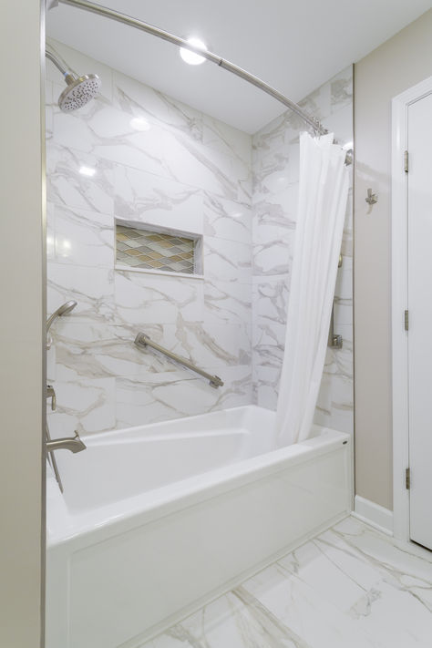 The client's main request was a bathtub for optimal relaxation. Our designer replaced the original walk-in shower with a deep tub and included a wall rail to make it more accessible. She then removed the soffits above the tub and sink to give the room height and make it feel open. She replaced the speckled shower surround with grey and white marble and installed a gold diamond shower niche. Our designer turned their bathroom into an oasis. Cultured Marble Shower, Granite Shower, Bathroom Tub Shower Combo, Deep Tub, White Marble Bathrooms, Bathroom Tub Shower, Wall Railing, Marble Showers, Large Vanity