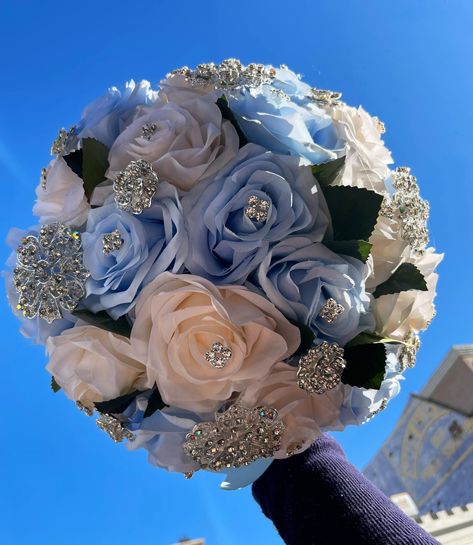 Handmade quinceañera bouquet made with ice blue and ivory artificial roses. Finished off with silver brooches. *Decor can be changed upon request* *This is a made to order bouquet* *Please note brooches can change in style based on availability* Sweet Sixteen Bouquet, Light Blue And Pink Quinceanera Ideas, Royal Blue And Pink Quinceanera Theme, Pink Blue Wedding Bouquet, Blue Pink And Silver Wedding, Blue And Pink Quinceanera Dress, Blue And Pink Quince Dress, Pink And Blue Party Theme, Pink And Blue Quinceanera Decorations