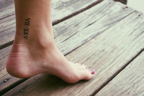 Roman numeral ankle tattoo Ankle Tattoo Roman Numerals, Places To Get Roman Numeral Tattoo, Ankle Roman Numeral Tattoo, Roman Numeral Ankle Tattoos For Women, Roman Numeral Tattoo On Ankle, Ankle Date Tattoo, Roman Numeral Ankle Tattoo, Ankle Number Tattoo, Number Tattoo Ankle