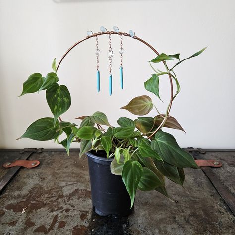 "This 100% copper circular plant trellis is perfect for any climbing plant or plant that requires a little extra support. Decorated with stones, this trellis features ocean blue sea glass, cut glass prisms, and turquoise spears. Trellis measures approximately 8.5\" tall and wide, with 3.5\" feet to fit into your planter. Each trellis is handmade; each raw stones color or size may vary. Plant not included." Diy Plant Trellis Indoor, Crystal Plant Trellis, Wire Plant Trellis, Diy Copper Plant Trellis, Copper Wire For Plants, Electroculture Gardening, Copper Trellis For Houseplants, Copper Plant Trellis, Plant Charms