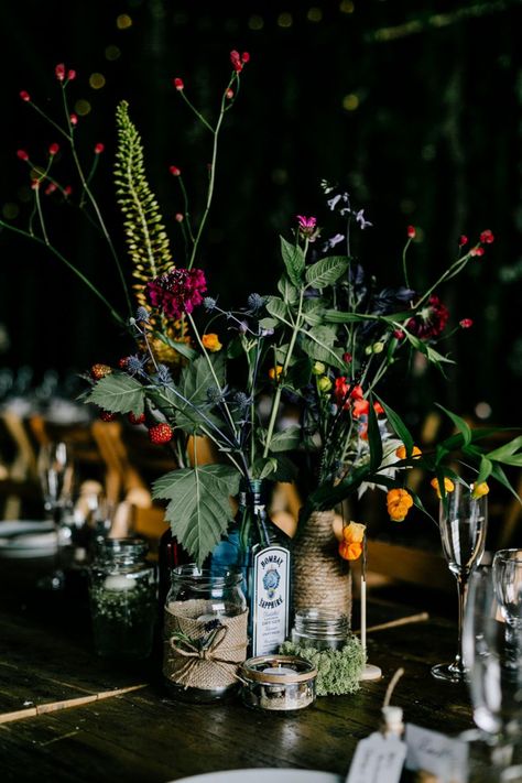 Alternative Wedding Table Centerpieces, Gin Bottle Flowers Wedding, Flowers In Gin Bottles, Alternative Wedding Table Decor, Flowers In Bottles Wedding, Meadow Theme Wedding, Gin Bottle Centrepiece, Flowers In Wine Bottles, Wedding With Bright Flowers