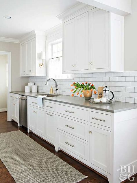 Preserving the galley-style kitchen layout eliminated the need to move plumbing or electric wiring—a budget-saver that allowed for new hardwood floors, cabinets, finishes, and appliances. A subway tile backsplash reflects light throughout and creates clean lines with newly painted cabinets. Stainless-steel appliances and drawer pulls keep the kitchen contemporary and ready for cooking. Cape Cod House Interior, White Galley Kitchen, Cape Cod Interior Design, Small White Kitchens, Gray Counter, Galley Kitchen Design, Galley Kitchen Remodel, Galley Style Kitchen, Diy Kitchen Renovation