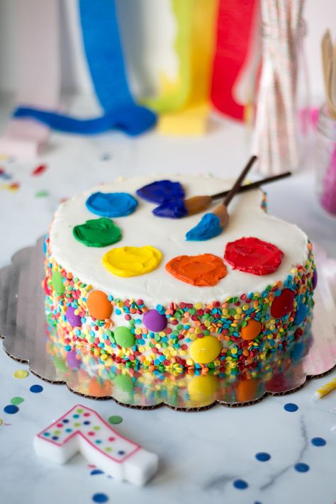 An art Palette Cake for an art themed birthday party! Sprinkled sides with a simple carving of the cake. Frosting ‘paint’ and paint brushes made from pocky cookies and Werther’s soft caramels. #cakedecorating #cakedecoratingfrosting #cake #artcake Art Cakes Birthday Artists, Paint Brush Birthday Cake, Arty Birthday Cake, Arts And Crafts Themed Birthday Party, Birthday Cake Art Theme, Painter Birthday Cake, Artist Palette Cake, Art Themed Birthday Cupcakes, Craft Themed Cake