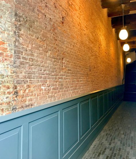 Exposed brick wall and reclaimed brick on the floor of a corridor in loft apartments. Exposed Brick Entryway, Exposed Brick Color Palette, Partially Exposed Brick Wall, Expose Brick Interior Design, Exposed Brick With Panelling, Painted Brick Wall Interior, Half Brick Wall Interior, Brick Wainscoting, Internal Brick Feature Wall