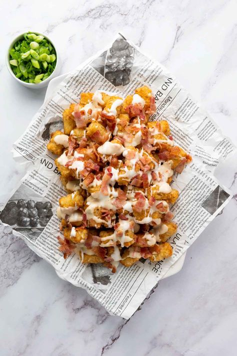 A plate of loaded tater tots with bacon bits and drizzled with cheese sauce, served on newspaper, with chopped green onions on the side. Tater Tots Appetizer, Loaded Tater Tots Recipes, Loaded Totchos, Loaded Tots, Tater Tot Appetizers, Tater Tot Nachos, Loaded Tater Tots, Tater Tot Recipes, Restaurant Appetizers