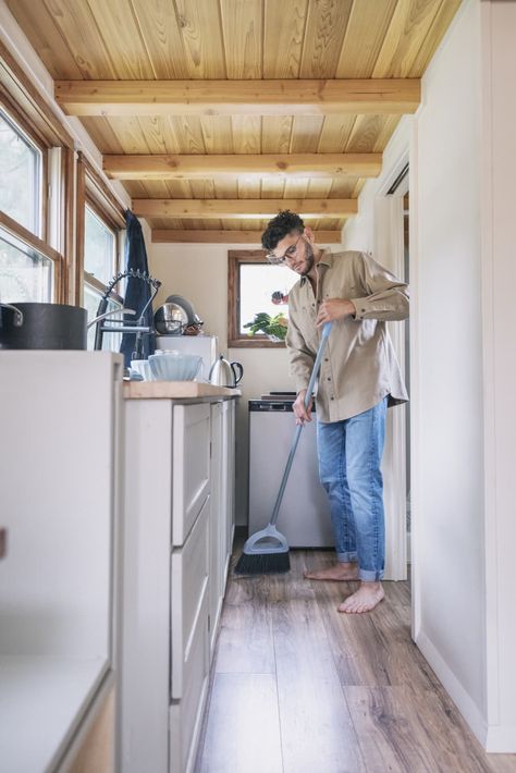 Young man sweeping floor in kitchen of tiny house Best Broom, Sweep The Floor, Messy Kitchen, Weekly Cleaning Schedule, Light Colored Wood, Clean Sweep, Weekly Cleaning, Weekend Projects, Closet Space