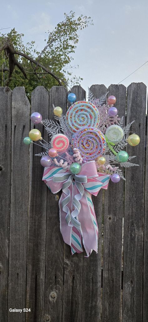 This tree topper is ready to be placed on your tree.. filled with lollipops and ball ornaments in beautiful pastel colors and finished with a large bow made with premium ribbon.  Pre-assembled and easy to install.  measures approximately 27inches long top to bottom check out the matching wreath here  https://designsbybvboutique.etsy.com/listing/1778463299/snowman-wreath-candyland-wreath-pastel ready to ship. Pastel Candy Christmas Decor Diy, Candyland Christmas Tree Topper, Candyland Tree Topper, Pastel Candy Christmas Decor, Candy Land Theme Christmas Tree, Candyland Theme Christmas Tree, Pink Candy Christmas Tree, Candy House Decorations, Candyland Christmas Decorations Outdoor