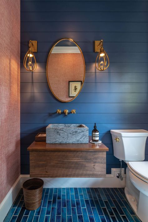 In this moody bathroom, navy blue shiplap walls with white base trim echo the hues in the blue floor tiles, which are finished with white grout. A handsome stone basin pairs with a floating wood vanity, and mixes with gold hardware, pendants, and mirror. Blue White Wood Bathroom, Blue Shiplap Bathroom, Bathroom Navy Blue, Blue Shiplap, Bathroom Navy, Floating Wood Vanity, Blue Floor Tile, Navy Blue Bathroom, Moody Bathroom