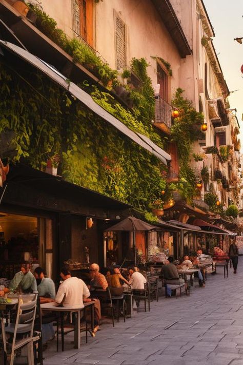 Sidewalk cafe and stalls in Italy, people at the tables having dinner in the evening, sun can be seen setting at the end of the street, lights are on the cafe and shops, plants and vines hanging from the walls https://apps.apple.com/us/app/genzart-ai-art-generator/id1669915100 Italy People, Vines Hanging, Sidewalk Cafe, Evening Sun, Street Lights, The Cafe, Art Generator, Vines, The End