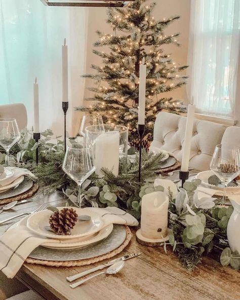 A magnificent tablescape includes masses of greenery and white tapered candles. Pine cone table decorations sit in the beige bowls at the place settings. A lit Christmas tree glows in the background...   Image: homesweetspaces Small Christmas Village Display, Small Christmas Village, Christmas Dinner Table Decorations, Dinner Table Decorations, White Living Room Decor, Paint Your House, Neutral Fall Decor, Christmas Dining Table, Mini Houses