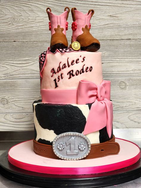 Pretty little cake for a 1st birthday, decorated in pink and brown, with a little cow print. The cowgirl boots topper was Rice Krispies Treats inside, fondant outside. The ribbon, bow, bandana, belt and buckle were also made of fondant. The bandana was hand-painted, although this picture doesn't show the pattern very well. But you can see more of the cake when you click the picture. The picture is linked to a video. There's also a matching smash cake. Cowgirl Birthday Cakes, Cowgirl Cakes, Rodeo Birthday Parties, Cow Birthday Parties, Farm Themed Birthday Party, Rodeo Birthday, Cowgirl Birthday Party, Cow Birthday, Barnyard Birthday